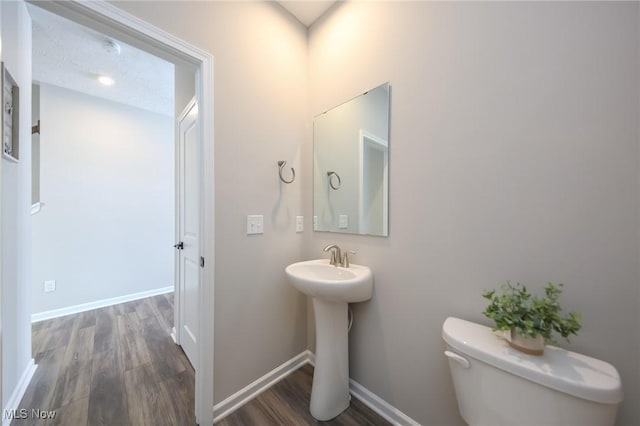 bathroom with baseboards, toilet, and wood finished floors