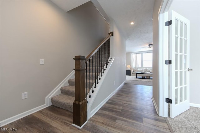 staircase featuring baseboards and wood finished floors