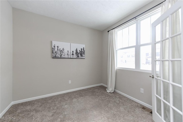 unfurnished room with baseboards, light carpet, and a textured ceiling