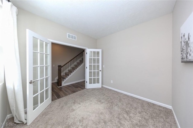 empty room featuring baseboards, french doors, visible vents, carpet floors, and a textured ceiling