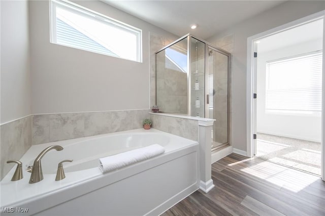 bathroom featuring wood finished floors, a stall shower, baseboards, recessed lighting, and a garden tub