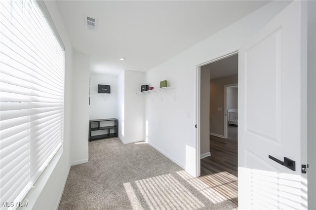 hall with carpet flooring, baseboards, and visible vents