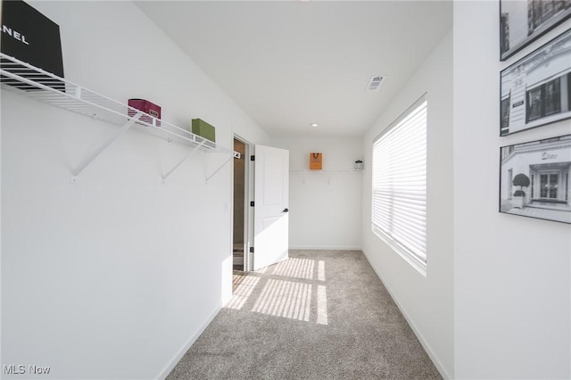 hall featuring baseboards and light colored carpet