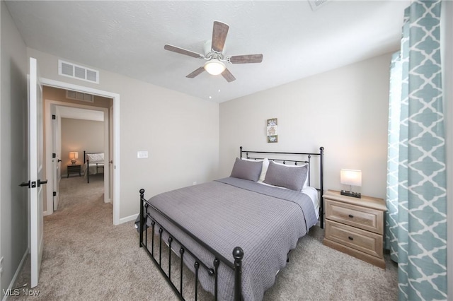 bedroom with baseboards, a ceiling fan, visible vents, and light carpet