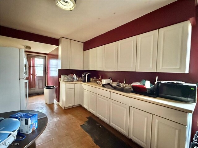 kitchen featuring white cabinets, light parquet floors, white fridge, and sink