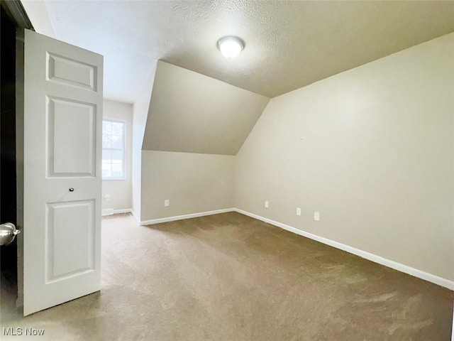 additional living space with carpet flooring, lofted ceiling, and a textured ceiling