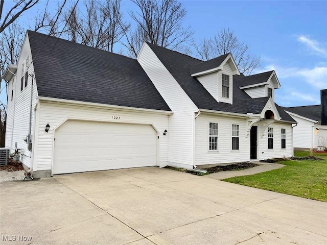 new england style home with central AC, a front yard, and a garage