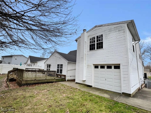 rear view of house featuring a wooden deck, a yard, and a garage