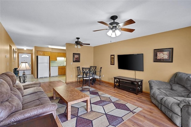 living room featuring light hardwood / wood-style flooring, ceiling fan, and sink