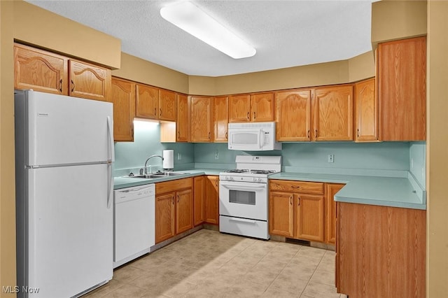 kitchen with a textured ceiling, white appliances, and sink