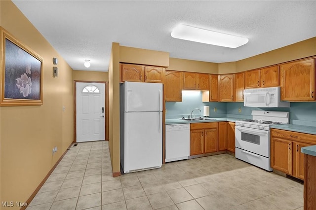 kitchen featuring a textured ceiling, white appliances, light tile patterned floors, and sink