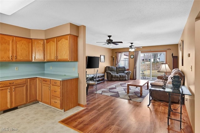 kitchen with ceiling fan, a textured ceiling, and light wood-type flooring