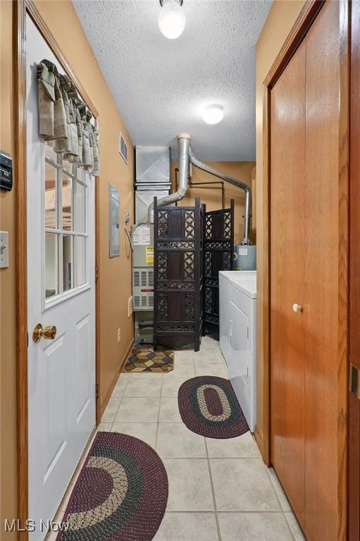 washroom with washer / dryer, light tile patterned floors, and a textured ceiling