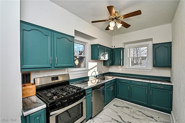 kitchen with sink, decorative backsplash, ceiling fan, a textured ceiling, and appliances with stainless steel finishes