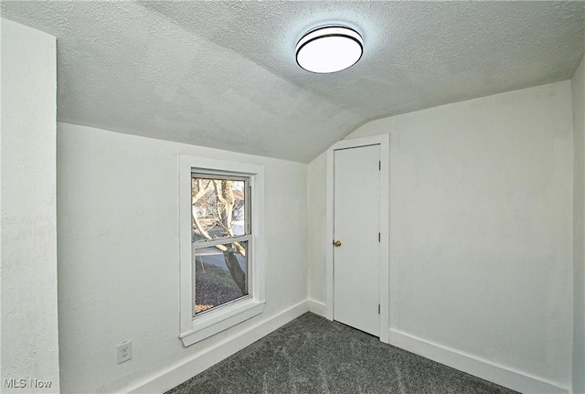 bonus room with dark colored carpet, a textured ceiling, and vaulted ceiling