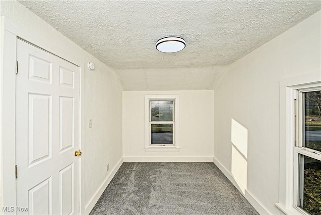 unfurnished room with a textured ceiling, carpet, and lofted ceiling