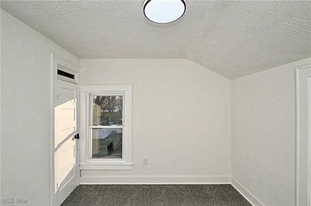 carpeted spare room with a textured ceiling and vaulted ceiling