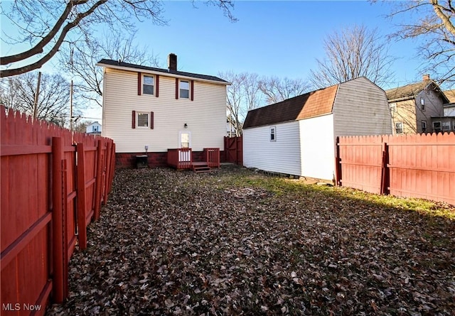 rear view of house with a shed and a wooden deck