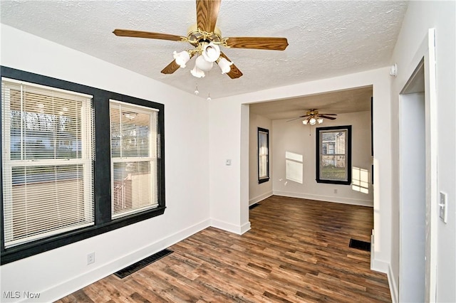 empty room featuring ceiling fan, dark hardwood / wood-style flooring, and a textured ceiling