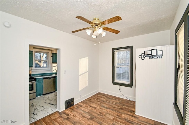 unfurnished bedroom featuring ceiling fan, wood-type flooring, and a textured ceiling