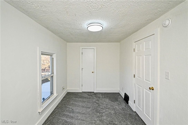 spare room with dark colored carpet and a textured ceiling