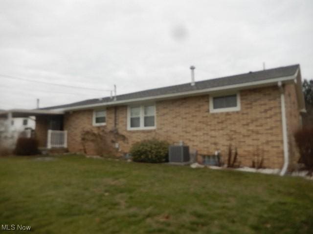 rear view of property featuring a lawn and cooling unit