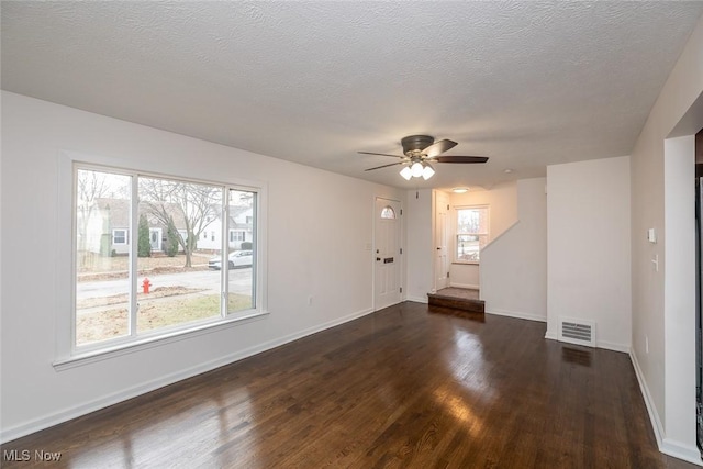 empty room with a textured ceiling, ceiling fan, and dark wood-type flooring