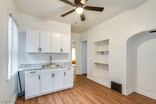 kitchen featuring white cabinets, built in shelves, light wood-type flooring, and sink