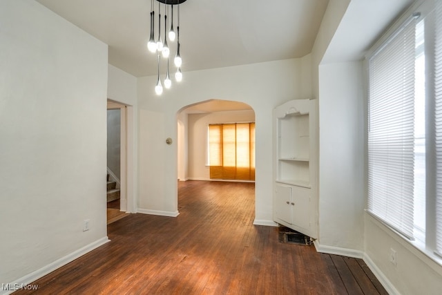 unfurnished dining area featuring dark hardwood / wood-style floors, a healthy amount of sunlight, and built in features