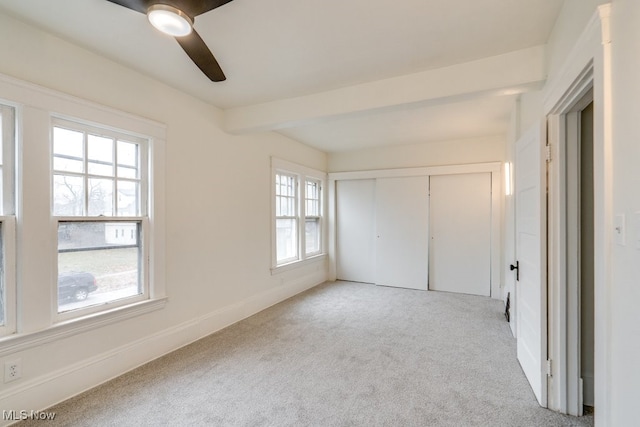 unfurnished bedroom with ceiling fan, multiple windows, light carpet, and a closet