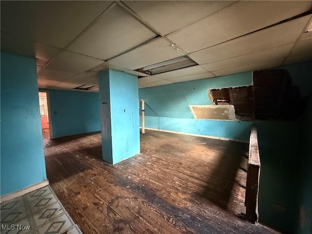 basement with a paneled ceiling and dark hardwood / wood-style floors