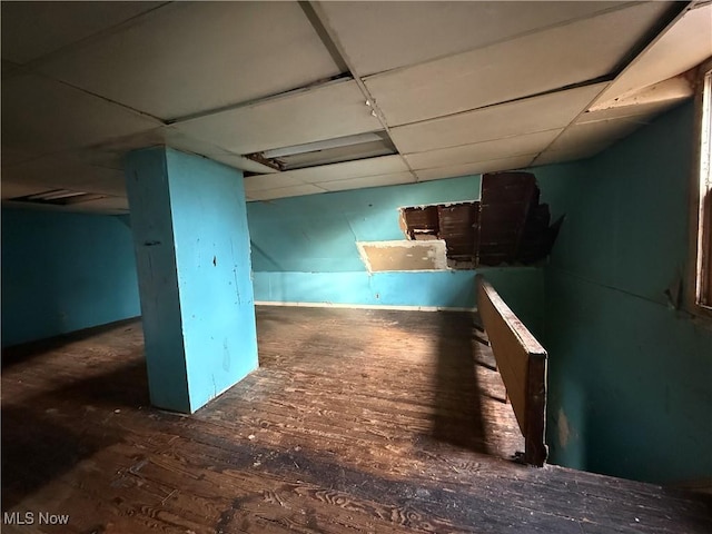 basement with a drop ceiling and dark hardwood / wood-style floors