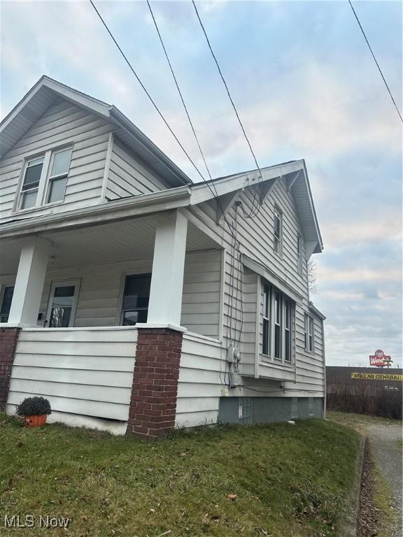 view of side of home with covered porch and a yard