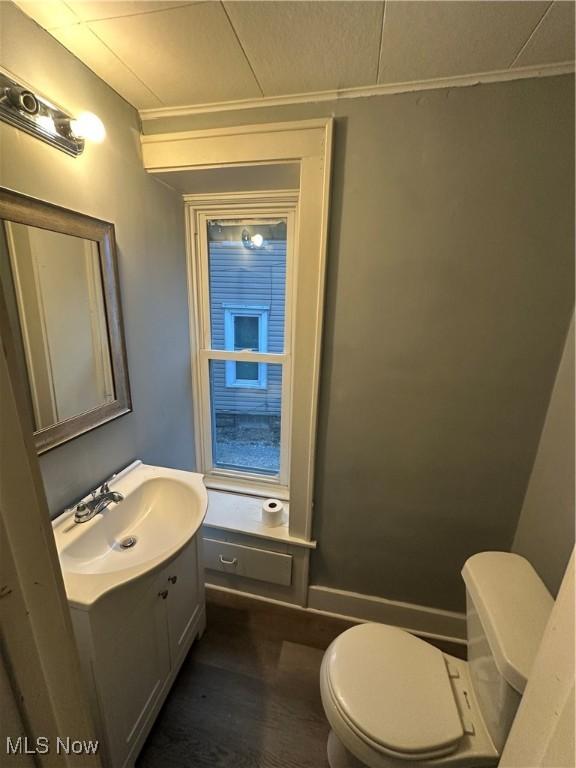 bathroom featuring wood-type flooring, vanity, toilet, and ornamental molding