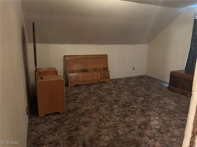 bonus room featuring dark carpet and vaulted ceiling