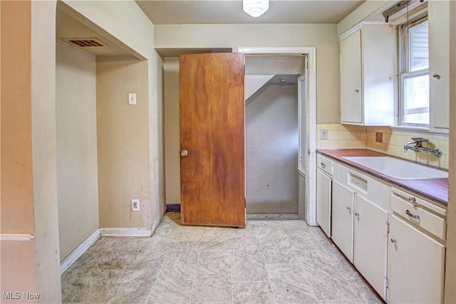 kitchen featuring white cabinets, decorative backsplash, and sink