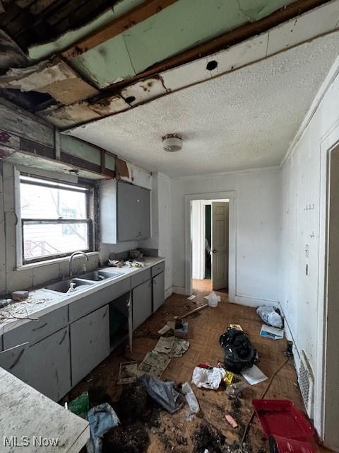 kitchen featuring dark parquet flooring, sink, and a textured ceiling