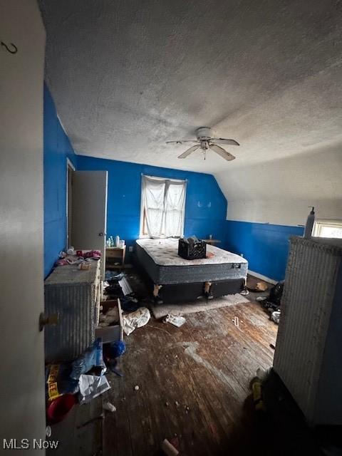 bedroom with a textured ceiling, ceiling fan, wood-type flooring, and lofted ceiling