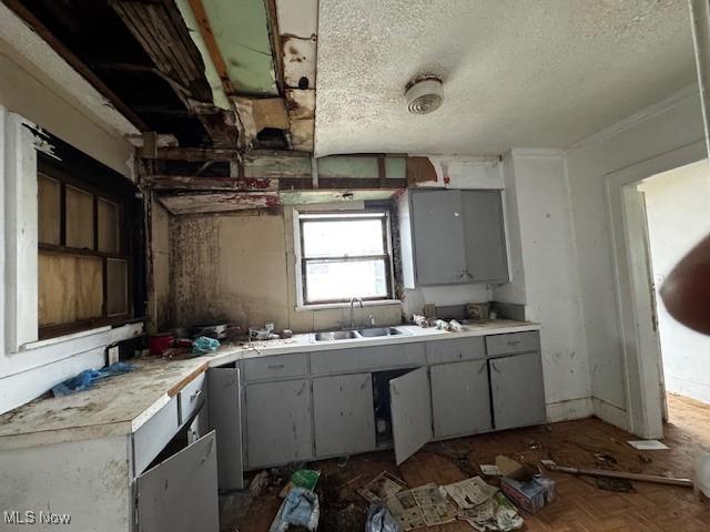 kitchen featuring a textured ceiling, dark parquet floors, gray cabinets, and sink