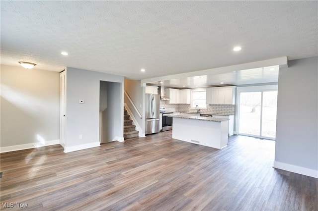 kitchen with hardwood / wood-style floors, white cabinets, sink, a kitchen island, and stainless steel appliances