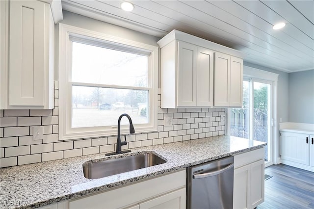 kitchen featuring dishwasher, sink, light stone counters, white cabinets, and hardwood / wood-style flooring