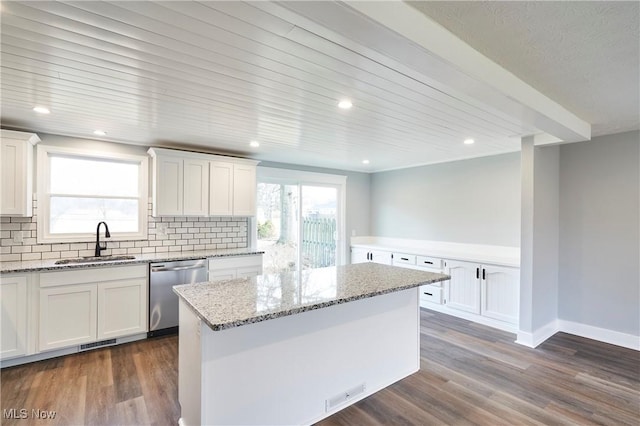 kitchen with a center island, sink, stainless steel dishwasher, light stone counters, and white cabinetry