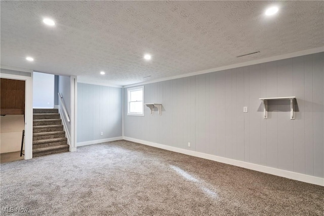 basement featuring carpet floors, a textured ceiling, and wooden walls