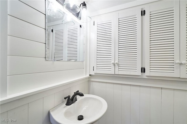 bathroom featuring wood walls and sink