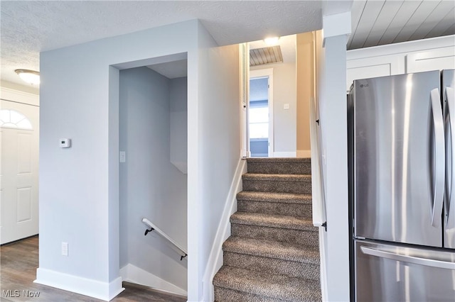 stairs featuring a textured ceiling and hardwood / wood-style flooring