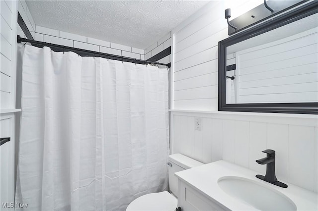 bathroom featuring walk in shower, vanity, a textured ceiling, and toilet