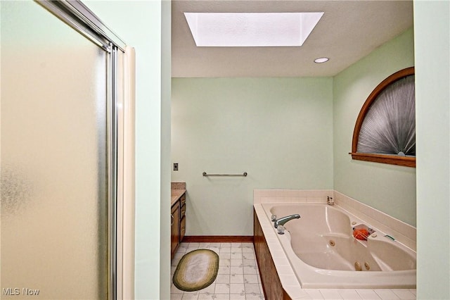 bathroom with vanity, a tub to relax in, and a skylight