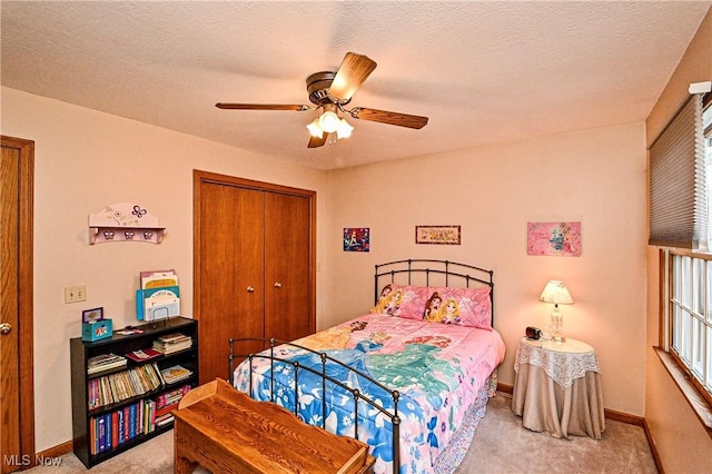 carpeted bedroom with ceiling fan, a closet, and a textured ceiling