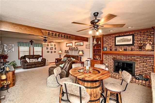 dining area with carpet flooring, a fireplace, a textured ceiling, and beamed ceiling