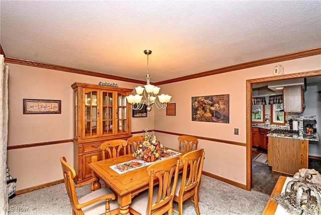 carpeted dining room with ornamental molding, a textured ceiling, and a chandelier